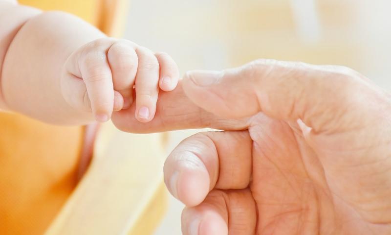 Persons and baby fingers touching